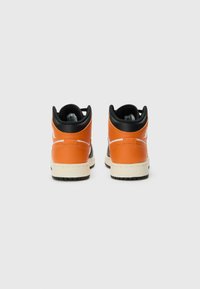Høytopp sneakers med oransje lær, svarte detaljer, hvite kontraster og en teksturert gummisåle.
