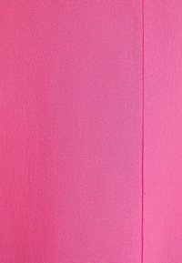 Fuchsia tyg med en slät, texturerad yta och en ren vertikal söm. Färgen är ljus och jämn utan mönster eller detaljer.