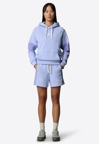 Ljuslila hoodie med framficka, matchande lila shorts, båda i textil med struktur, med en logopatch och vita snören.