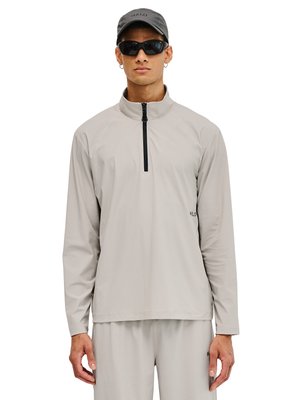 Mand iført lysegrå langærmet pullover med frontlynlås, matchende bukser, sorte solbriller og grå kasket med "HALO" logo.