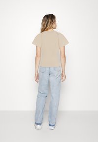 Beige topp med puffede ermer, tettsittende liv, kombinert med lyseblå høyhogsjeans. Antrekket passer til en uformell stil.