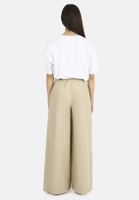 Cream wide-leg trousers with an elastic waistband, paired with a white short-sleeve t-shirt. Smooth fabric with a relaxed fit.