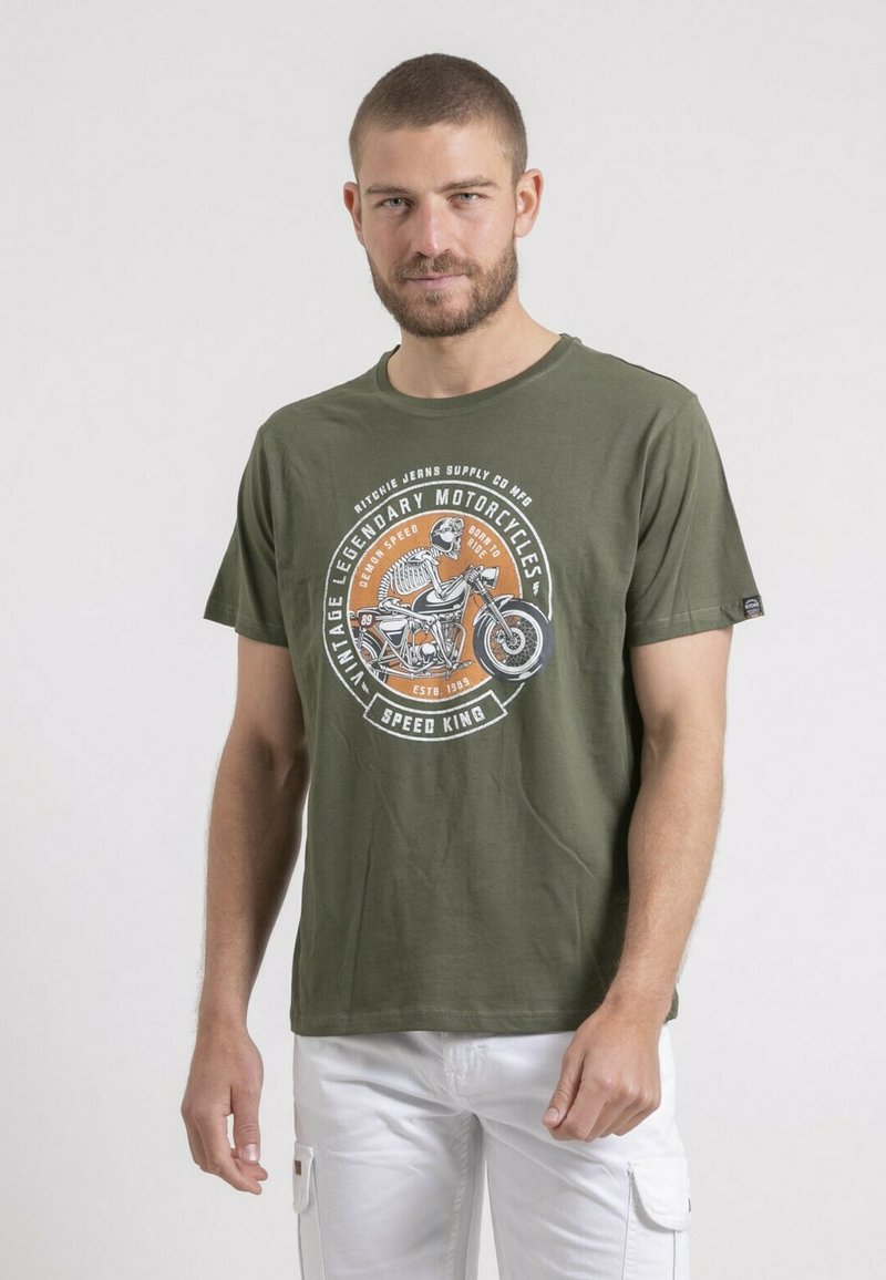 T-shirt en coton vert olive avec un col rond et des manches courtes. Présente un grand motif d'une moto et du texte en blanc et orange.