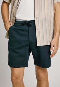 Pantalones cortos de algodón ligero en azul marino con cintura elástica y cordón. Cuenta con bolsillos laterales y detalle de dobladillo doblado.