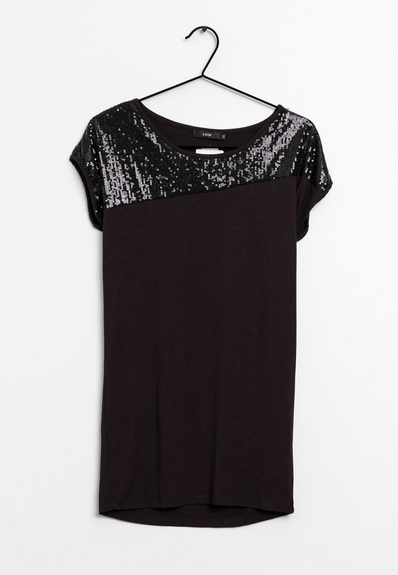 T-shirt noir avec un panneau supérieur en sequins, col rond, manches courtes, tissu doux et coupe droite. Suspendu à un crochet noir.