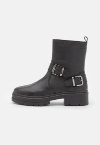 Black leather ankle boot with textured finish, two adjustable metal buckles, and a sturdy rubber sole. Features a back pull tab.