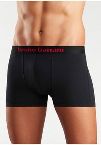 Schwarze Boxershorts aus glattem Stoff, ausgestattet mit einem breiten schwarzen Bund, auf dem "bruno banani" in roter Schrift steht.