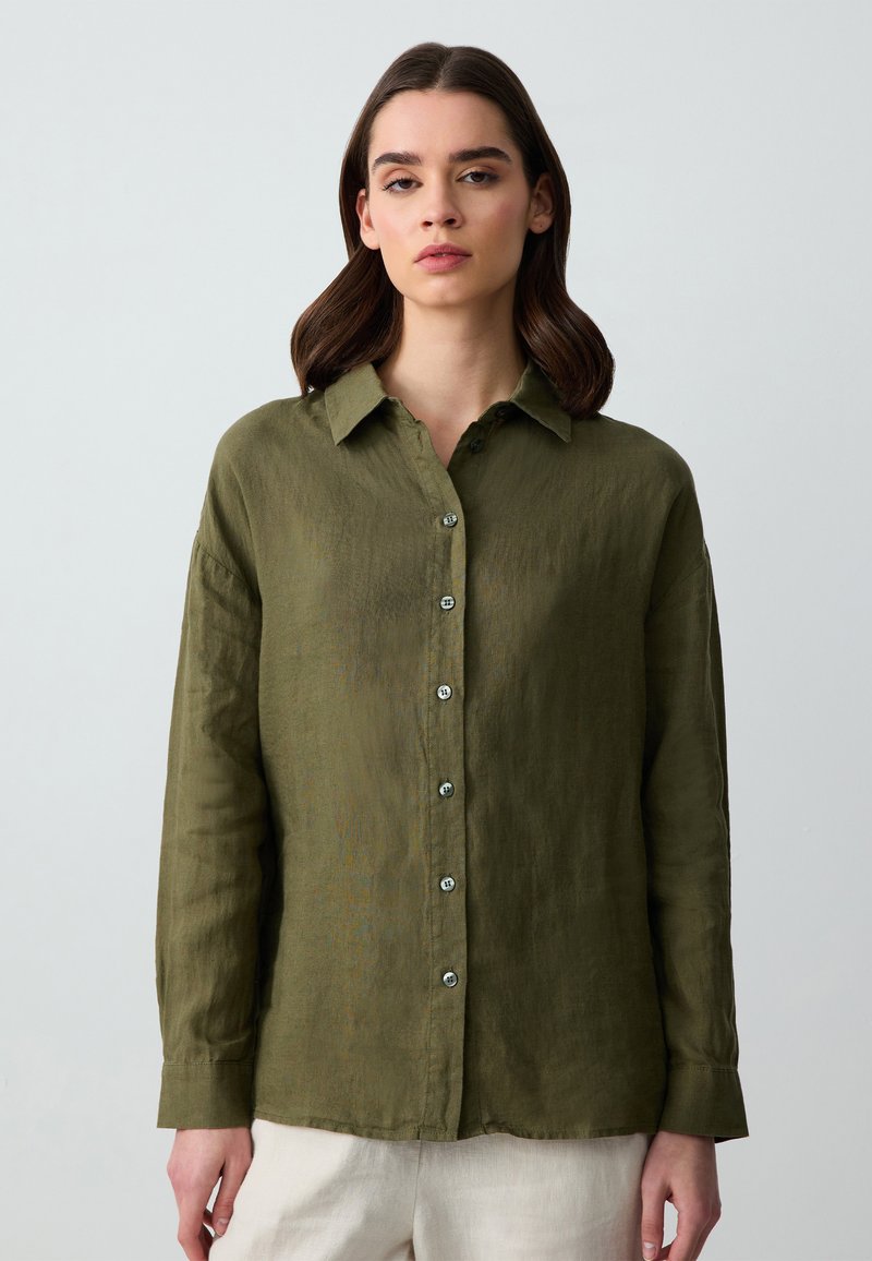 Camicia verde oliva con bottoni, realizzata in tessuto leggero, dotata di colletto, maniche lunghe e bottoni argentati lungo la parte anteriore.