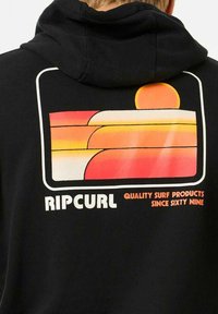 Zwarte hoodie met een kleurrafie van gelaagde strepen in oranje en roze met een zon, en de tekst "RIPCURL QUALITY SURF PRODUCTS SINCE SIXTY NINE".