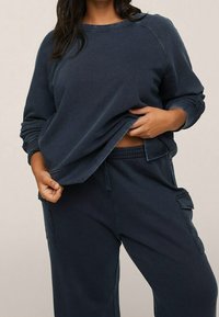 Sweatshirt bleu marine avec des manches raglan, texture douce et col rond, assorti de joggers bleu marine avec des poches latérales.