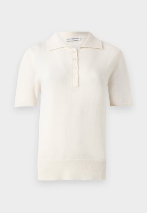 Polo de manga curta, de cor creme, feito de um tecido de malha suave, com uma pala de três botões e bainha canelada.