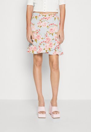 Kwiatowa spódnica na jasnoniebieskim tle, zdobiona różowymi różami i zielonymi liśćmi, z falbaniastym dołem i dopasowanym pasem. Połączona z różowymi butami na platformie.