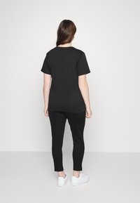 Černé tričko s krátkým rukávem a černé slim-fit kalhoty, doplněné bílými teniskami. Jednoduchý design; měkká tkanina; střední délka.