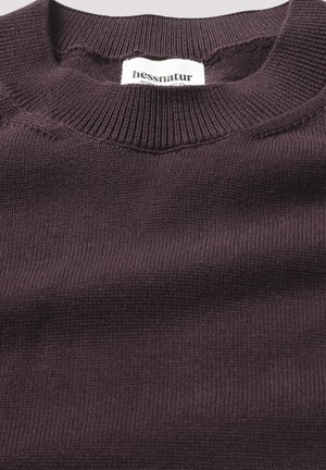 Dunkellila Pullover mit rundem Ausschnitt und gerippten Bündchen. Weiche Stricktextur mit einem Etikett, das "hessnatur" in der Nähe des Kragens zeigt.