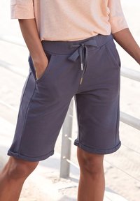 Navy Shorts aus einem Baumwollgemisch mit umgeschlagenen Säumen, einem Kordelzugbund und Seitentaschen. Weiche Textur und lockere Passform.