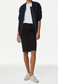 Marineblaue Bomberjacke, weißes T-Shirt, schwarzer Bleistiftrock und hellbeige Sneaker, kombiniert für einen lässigen, modernen Look mit klaren Linien.