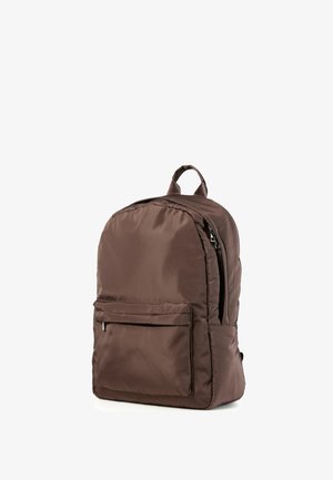 Brauner Nylonrucksack mit einer Reißverschlusstasche vorne und einem oberen Griff, dargestellt stehend auf weißem Hintergrund.