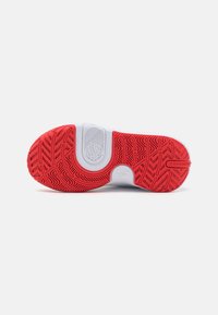 Podeszwa sportowego buta w kolorze czerwonym i białym. Posiada teksturowany gumowy wzór dla lepszej przyczepności oraz wyraźne logo i wypukłe akcenty dla zwiększenia trwałości.