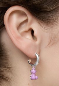 Boucle d'oreille en argent avec un charme ourson en gomme rose. La texture est lisse ; le charme présente des formes arrondies, ajoutant un élément de design ludique.