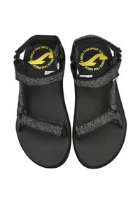 Sandalias negras con suelas texturizadas, que cuentan con correas ajustables en un patrón geométrico y un logo en la plantilla.