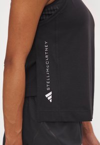 Camiseta sin mangas deportiva negra con un corte relajado, que presenta un audaz logo blanco "STELLA McCARTNEY" y detalles a rayas en el hombro.