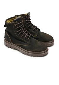 Botas de ante marrón hasta el tobillo con cordones marrones, suelas de goma y un forro amarillo en contraste. Costuras reforzadas y un detalle de talón texturizado.