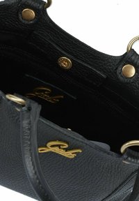 Bolso de mano de cuero negro texturizado con un logo dorado, que cuenta con un compartimento con cremallera, herrajes de latón y correas laterales para llevar.