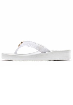 White flip-flop with a cushioned sole, fabric straps, and a gold round accent. Smooth texture with a flat profile and ridged sole for traction.