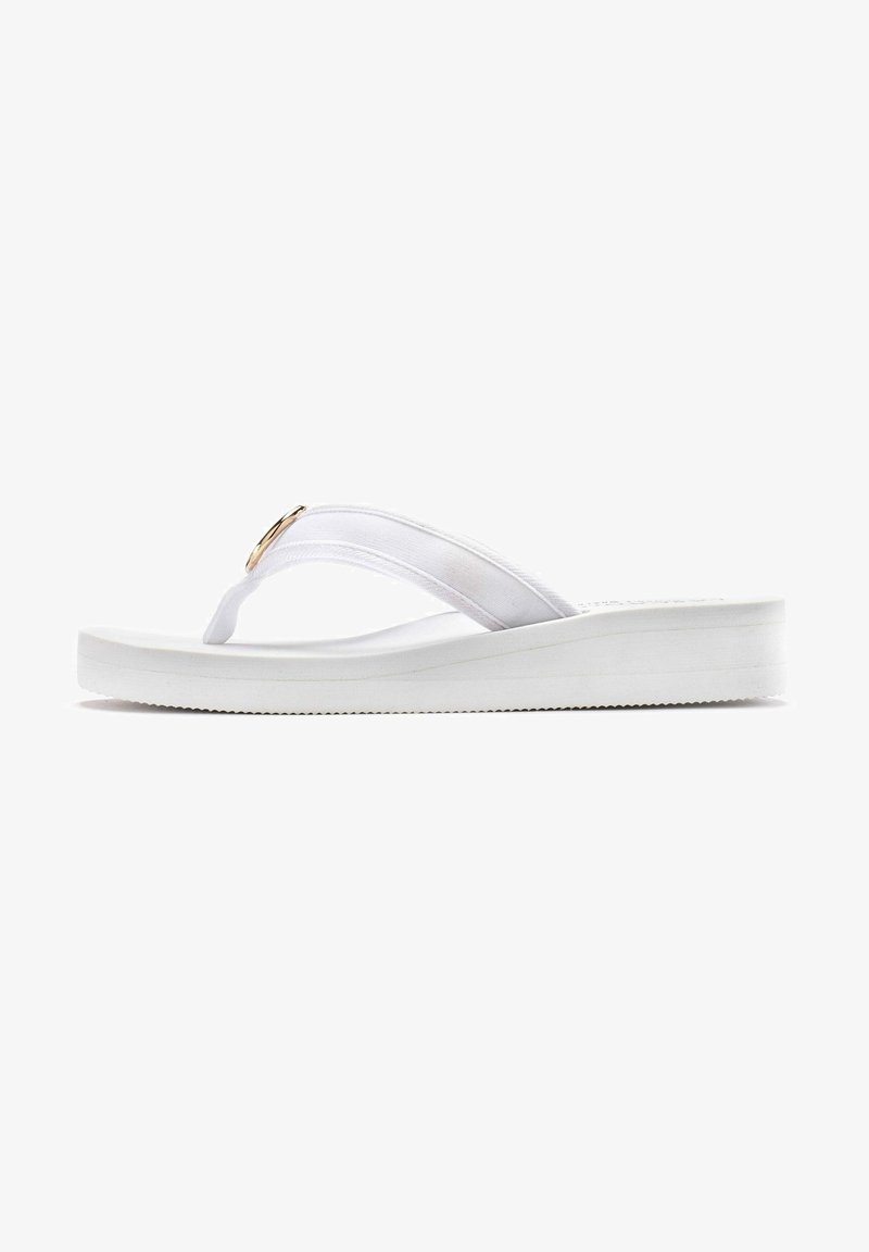 Witte flip-flop met een gevoerde zool, stoffen banden en een gouden ronde accent. Glad oppervlak met een vlak profiel en een gegroefde zool voor grip.