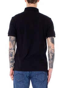 Svart polo-shirt med korte ermer, en klassisk krage og en glatt tekstur. Bært med blå jeans, som viser intrikate tatoveringsdesign på armene.