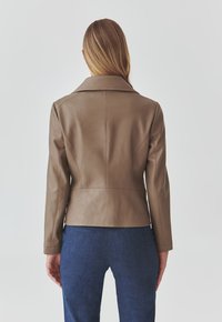 Brown leather jacket with a fitted design, notched collar, and long sleeves. Smooth texture, accentuated seams, and a cropped length.