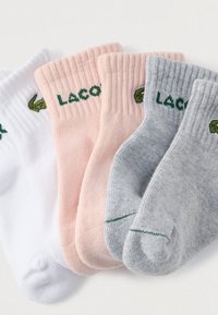 Τέσσερα ζευγάρια ριμπ κάλτσες σε λευκό, ροζ, ανοιχτό γκρι και σκούρο γκρι, με πράσινη κεντημένη λογότυπο Lacoste. Μαλακό υλικό με μείγμα βαμβακιού.