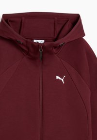 Burgundy zip-up hoodie with a smooth texture, featuring a white logo and a structured hood. Designed with raglan sleeves for a relaxed fit.