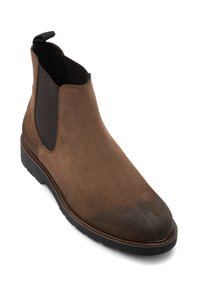 Botine Chelsea din suede maro, cu panouri elastice pe laterale, vârf rotund, tab de tragere și o talpă robustă din cauciuc negru. Finisaj ușor uzat.