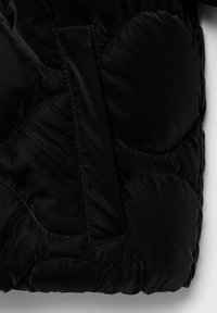 Črna puffer jakna, ki prikazuje prešito teksturo s krožnimi vzorci in navpično zanko. Gladek material z vidnimi šivi.