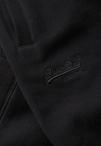 Zwarte katoenen sweatshirt met een textuur en geborduurd "SuperDay" logo. De stof voelt zacht aan met een gladde afwerking en heeft een standaard pasvorm.