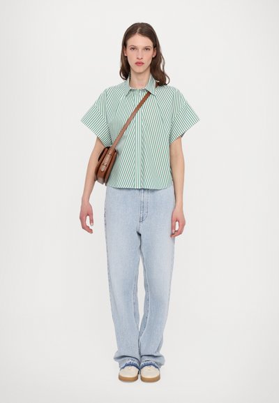 Green and white striped short-sleeve shirt paired with light blue straight-leg jeans and a brown crossbody bag.