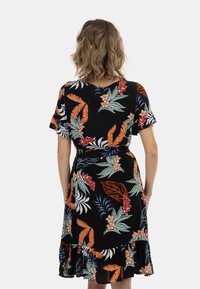 Rochie neagră cu imprimeu floral, cu mâneci scurte, având modele tropicale vibrante în nuanțe de roșu și verde și o margine ondulată. Fabricată dintr-un material ușor.
