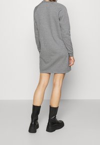 Vestido sudadera gris con mangas largas, puños acanalados y un escote redondeado, combinado con botas negras altas hasta la rodilla. Tejido suave y casual.
