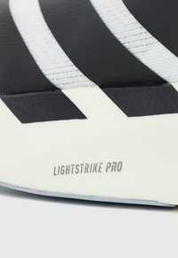 Gros plan d'une semelle de chaussure blanche et noire avec "LIGHTSTRIKE PRO" imprimé sur la zone de la semelle intermédiaire.