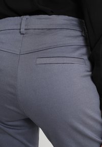 Grå tygbyxor med slim fit, med en diskret bakficka och slät textur, kompletterade av en mid-rise midja.