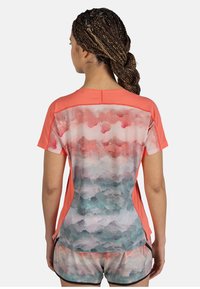 Coral athletic shirt features a mesh back with a gradient pattern in pink and blue hues. Short sleeves and side slits enhance breathability.