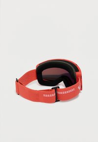 Červené lyžiarské okuliare s čiernou penovou výstelkou a nastaviteľným červeným pásom s bielymi cik-cak a vlnkovými vzormi na bielom pozadí.