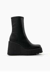 Black wedge ankle boot made of smooth leather, featuring a rounded toe, a high platform sole, and an elastic top for snug fit.