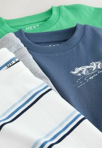 Négy hajtogatott, kerek nyakú pulóver tornya: zöld, versenyautó mintás tengerészkék, szürke és kék csíkos fehér.