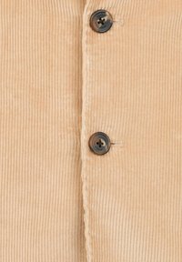 Sametová tkanina v světlé béžové barvě s výrazným vertikálním žebrováním, s dvěma tmavými knoflíky uprostřed a šitým švem podél okraje.