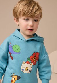 Turkusowa bluza z kapturem z kolorowymi wzorami zwierząt z kreskówek: fioletowy ślimak, niedźwiedź, lew i kolorowa sarna. Miękki materiał, luźny krój.