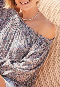 Blomstret off-the-shoulder bluse med lilla, pink og grønne mønstre. Textureret stof med samling ved halsudskæringen og ærmerne.
