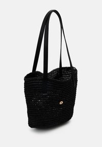 Musta kudottu kantokassi nahkahandleilla, pyöreä muoto, avoin yläpää ja pieni puukoriste. Rakenteellinen pinta ja tilava sisäosa.