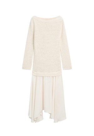 Kremowy, długorękawowy sweter z dzianiny połączony z zwiewną, asymetryczną kremową spódnicą na białym tle.